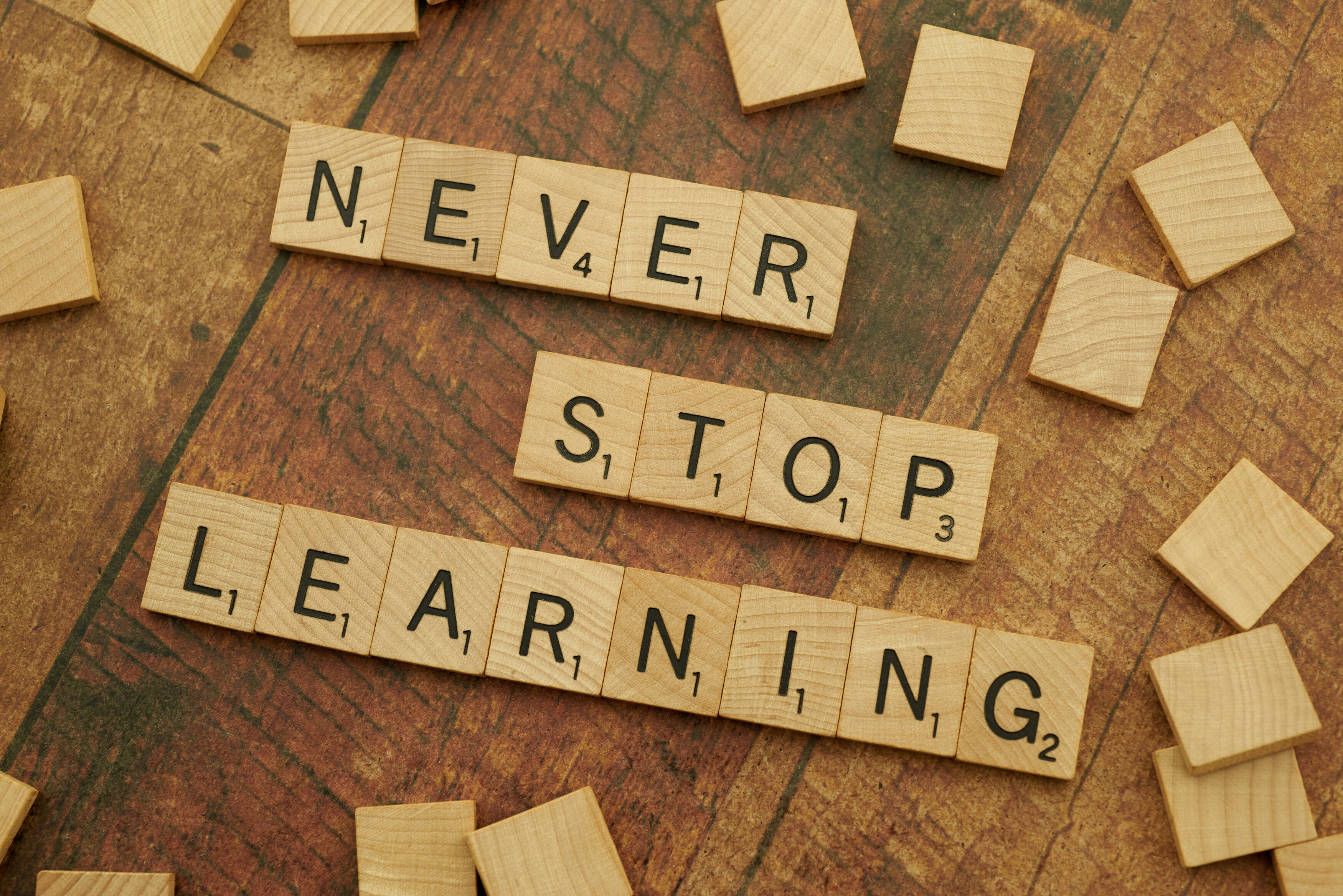 Scrabble Board Letters spelling out "Never Stop Learning"