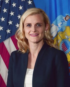 Board Chair Sarah Godlewski posing in front of USA and Wisconsin flags