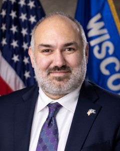 Board member John Leiber posing in front of USA and Wisconsin flags