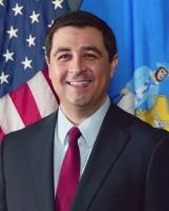 Board member Josh Kaul posing in front of USA and Wisconsin flags