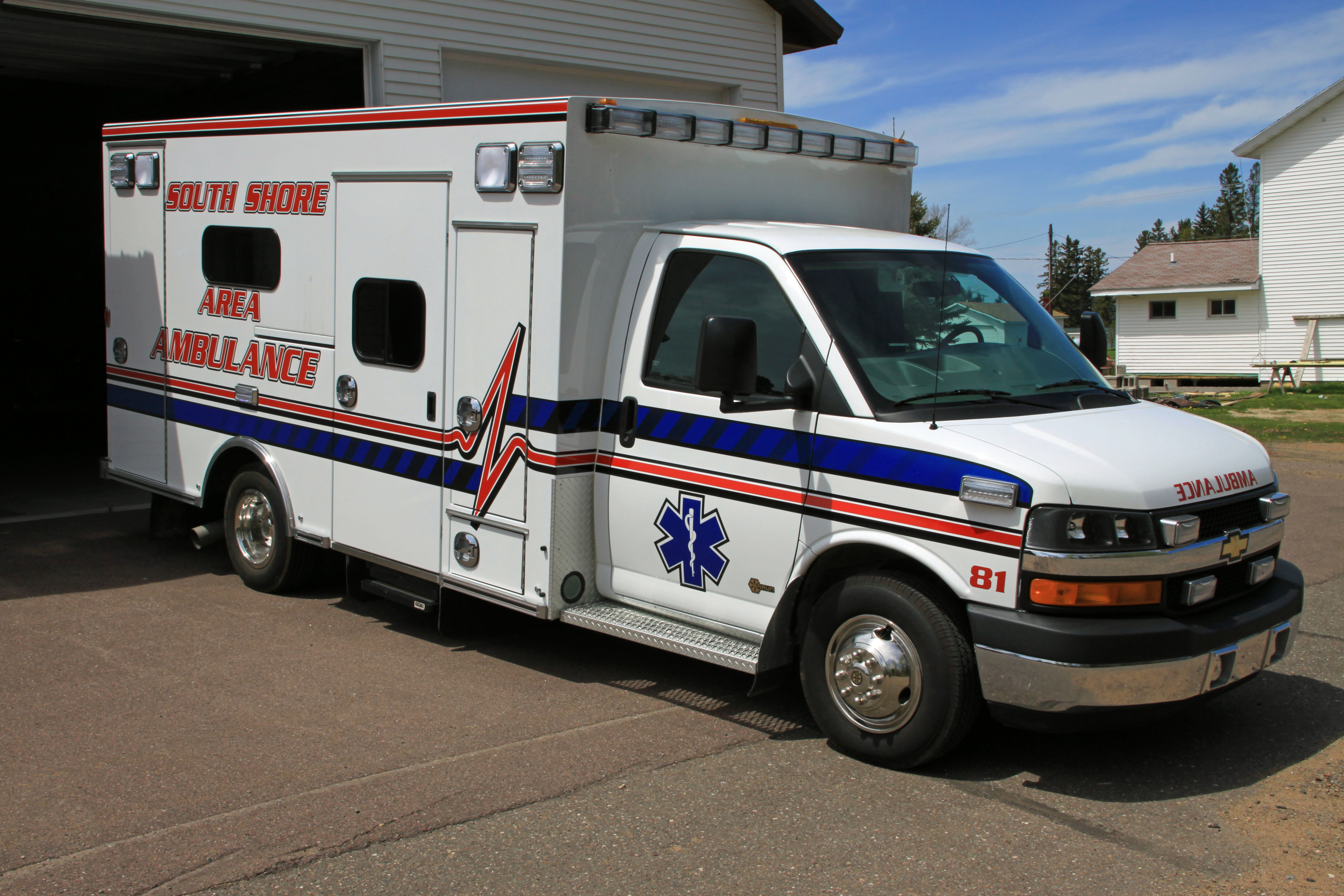 Driver side view of the Bayfield County South Shore Ambulance - white with red and blue stripes