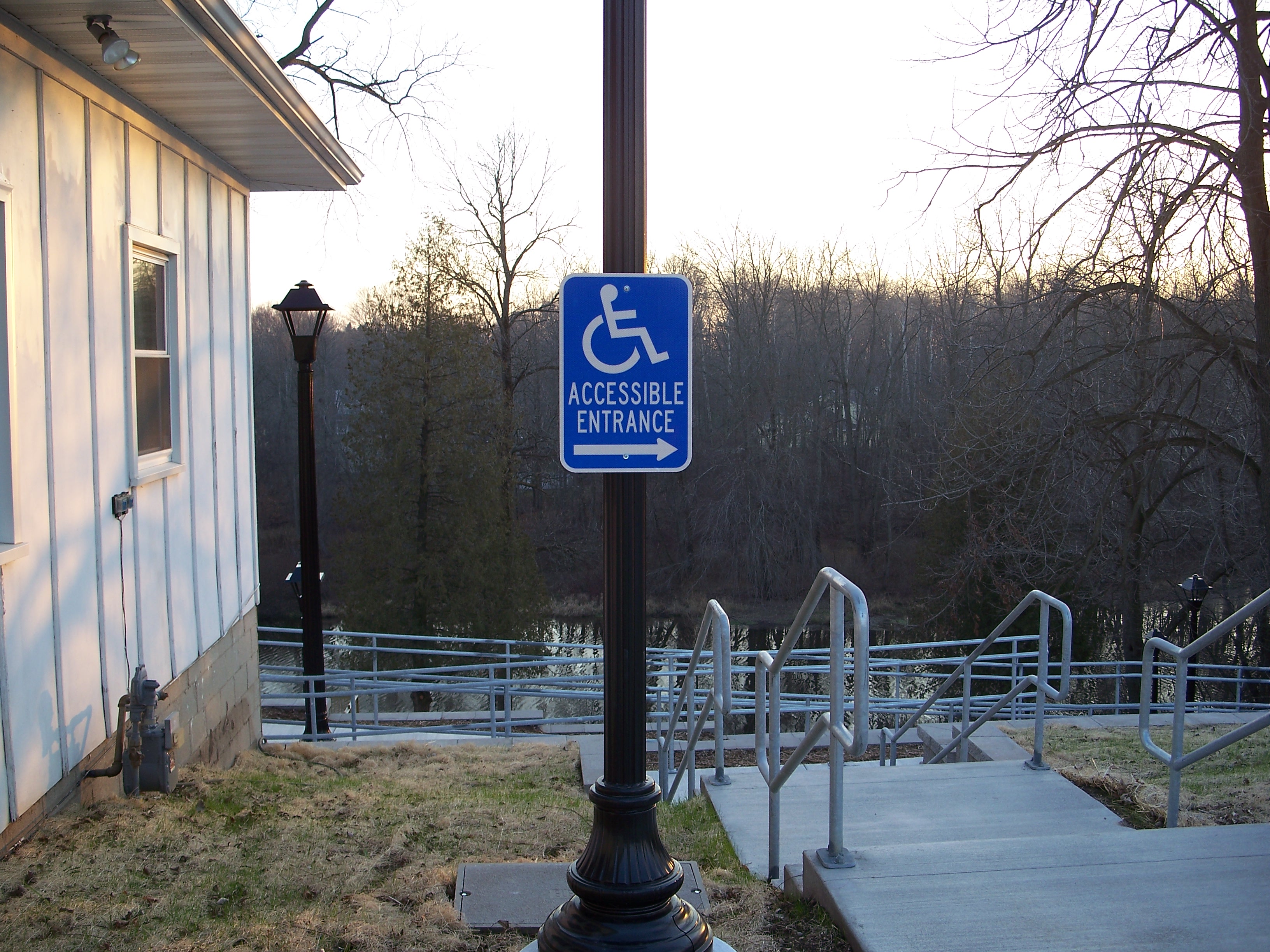 Village of Mishicot handicap ramp entrance area with Accessible Entrance sign and railing.
